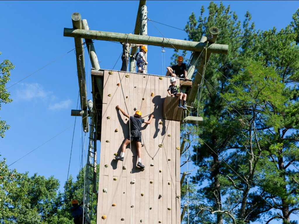 Boys climbing on rock climbing wall at grief camp